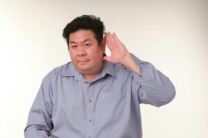 A man in a pose demonstrating the gesture of listening in a studio setting.
